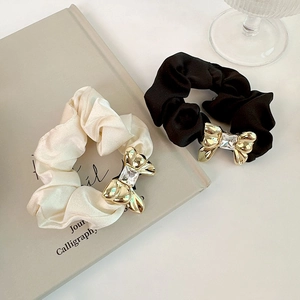 Detailed shot of silk hair scrunchies with golden metal bow and sparkling crystals
