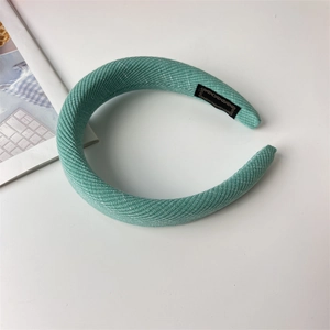 Detail of mint green padded sponge headband with fine ribbed fabric and branded woven label