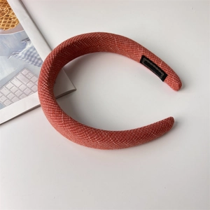 Detailed close-up of thick brick red sponge headband with ribbed fabric texture and inner tag