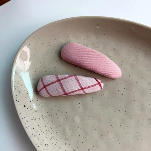 Set of two candy-colored plaid and pink fabric hair clips on a ceramic plate