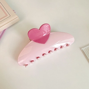 Detail of a large pink claw clip with heart decoration and smooth acrylic texture