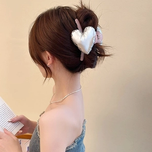 Detailed view of large silver 3D heart hair claw clip styled on model back hair