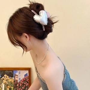 Silver metallic puffed heart hair claw clip shown styled in a neat bun hairstyle
