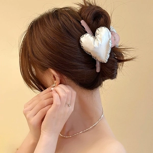 Detail of silver 3D heart hair claw clip with pink resin base on brown hair