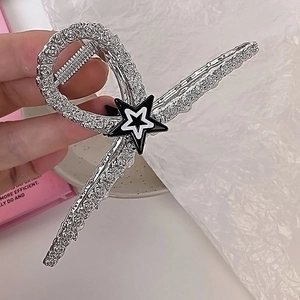 Détail d'une grande pince à cheveux étoile argentée avec texture en alliage tenue à la main