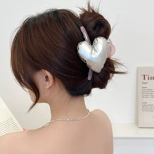Close-up of a large metallic silver 3D heart hair claw clip on a stylish updo hairstyle