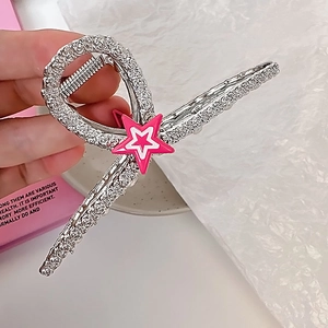 Détail de la pince à cheveux en métal avec étoile en strass rose et ressort fort