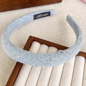 Elegant light blue tweed headband with thick sponge padding on a wooden jewelry display stand