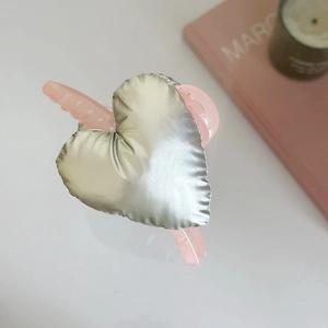 Top view of a pink translucent shark hair clip with a large puffy silver heart detail