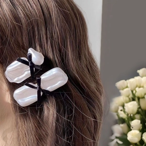 Elegant pearl acrylic hair clip set with black velvet bows on long brown hair