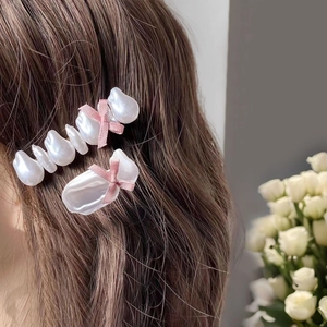 Baroque pearl hair clips with pink satin bows shown on model with brown wavy hair