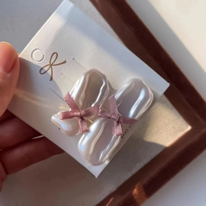 Detailed close-up of an irregular pearl earring with a delicate pink satin ribbon bow