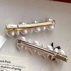 Close-up of elegant pearl hair clips with pink and black ribbon bows on gold metal
