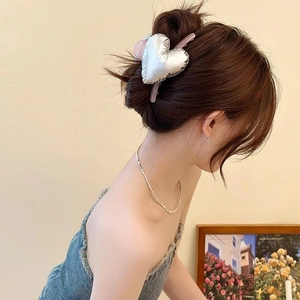Chic oversized silver 3D heart claw clip on model's hair with a soft pink base