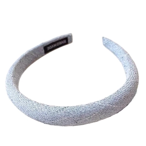 Elegant light blue sponge headband with textured fabric and handmade label on white background