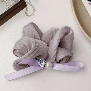 Elegant purple pleated scrunchie with a satin bow, pearl, and crystal on light background