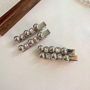 Détail de quatre pinces à cheveux argentées avec cristaux carrés roses et perles métal