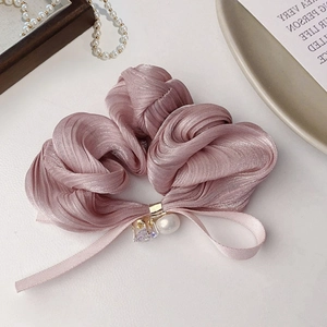 Pink pleated scrunchie with pearl pendant and silk ribbon on a white elegant table