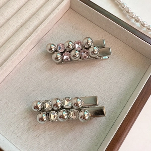 Détail de pinces à cheveux argentées avec cristaux roses et clairs sur plateau à bijoux