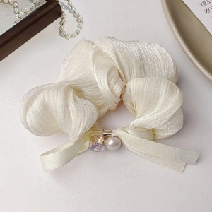 Detailed close-up of cream pleated hair scrunchie with pearl and lavender crystal charm