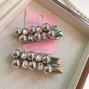 Détail de barrettes argentées avec cristaux roses et perles sur carte de présentation