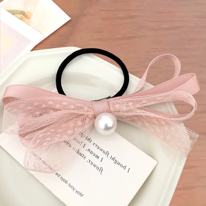 Elastico per capelli in pizzo rosa con fiocco, perla e pois su piatto di ceramica bianca