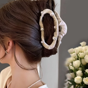 Détail de la pince à cheveux en soie champagne avec perles blanches pour chignon élégant