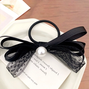 Dettaglio di elastico per capelli con fiocco di pizzo nero e perla bianca elegante
