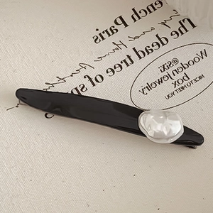 Pince à cheveux noire minimaliste avec détail perle sur tissu de style français