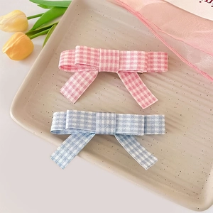 Barrettes à cheveux à carreaux rose et bleu au style vichy sur un plateau décoratif