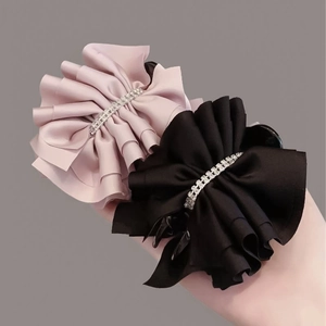Détail de pinces à cheveux en satin plissé rose et noir avec strass argentés brillants