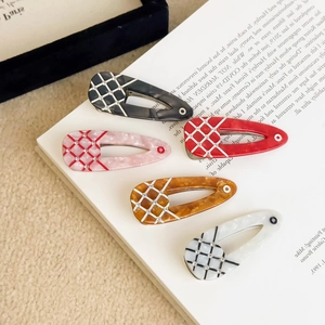 Set of five colorful lattice acetate hair clips with rhinestones on an open book