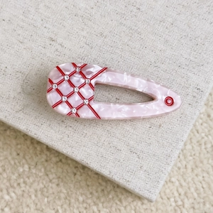 Macro shot of pink marble acetate hair clip with red checkered pattern and crystals