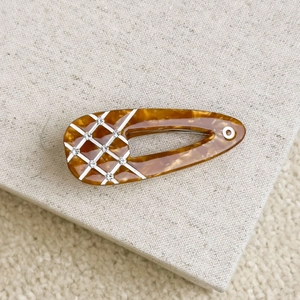 Detail of tortoiseshell acetate drop-shaped hair clip with white plaid and crystal accents