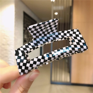 Gros plan d'une grande pince à cheveux à damier noir et blanc au design géométrique creux