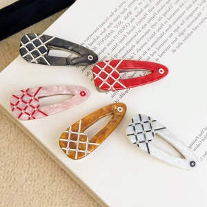 Set of five colorful marble acetate hair clips with rhinestone grid patterns on a book