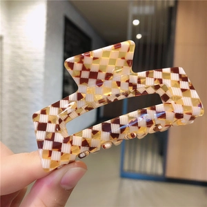 Détail d'une grande pince à cheveux en acétate avec motif en damier marron et blanc