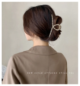 Dettaglio della grande pinza per capelli in metallo dorato con strass su uno chignon
