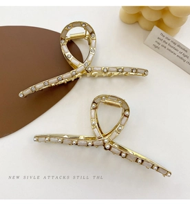 Dettaglio di fermagli per capelli in metallo dorato con eleganti perle e strass