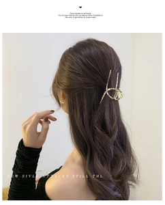 Dettaglio di una grande pinza per capelli in metallo dorato su capelli mossi castani