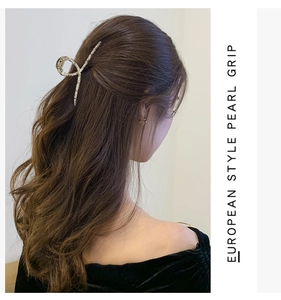 Dettaglio di una pinza per capelli dorata geometrica con perle su capelli mossi