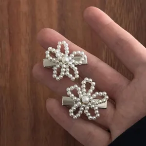 Détail de deux pinces à cheveux fleurs en perles avec base en métal argenté