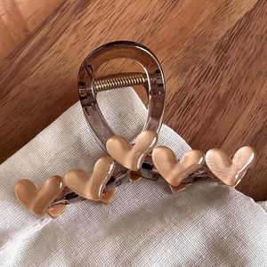 Pince à cheveux coréenne avec cœurs marron perlé sur fond en tissu et bois sombre