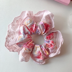 Detail eines rosa geblümten Spitzen-Scrunchies mit Herzprint und Schleifenstruktur
