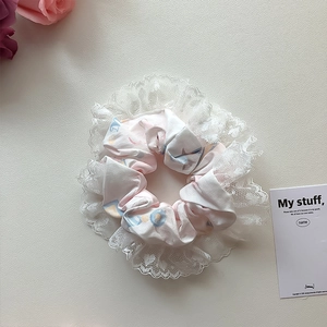 Detail eines rosa Haar-Scrunchies mit Blumenmuster und weißem Spitzenbesatz