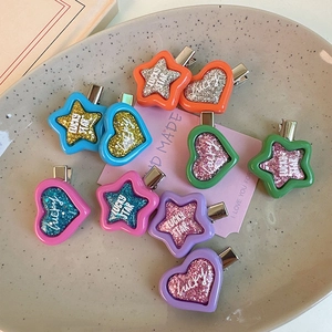 Macro shot of colorful glittery star and heart Y2K hair clips on a ceramic plate
