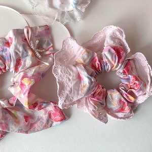 Detailansicht der rosa Haargummis mit Herzmuster, Spitzenbesatz und Perlenkreuz-Anhänger
