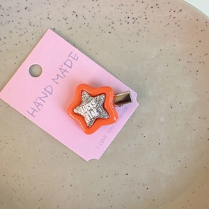 Detail of glittery orange star hair clip with Lucky Star text on card holder
