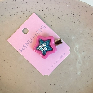 Close-up of pink star hair clip with blue glitter and Lucky Star text on card