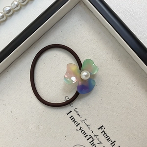 Détail d'un chouchou floral avec pétales en acétate irisé et accent de perle centrale